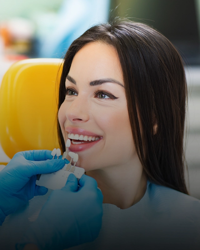 A woman smiling while a doctor matches her tooth color to color samples