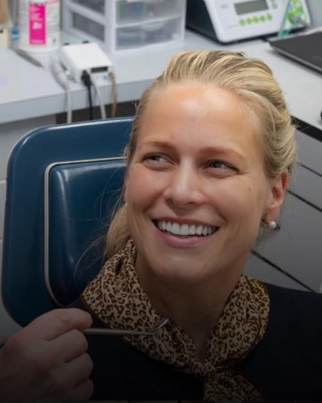 A smiling patient in a dental exam chair